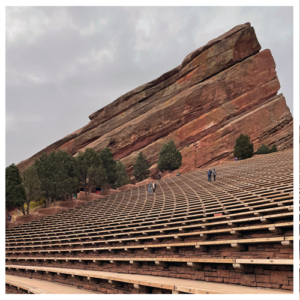 Empty Red Rocks amphitheater with curved bench seats and a large red rock rising in the background