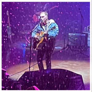 Zach Bryan performing on stage at Red Rocks in the snow
